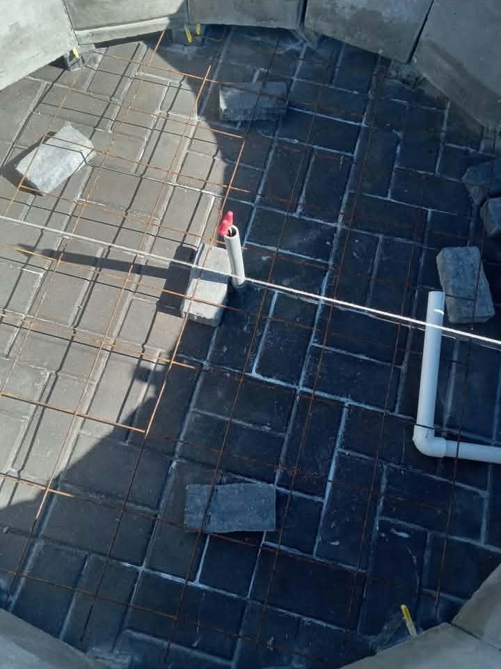 Paver floor inside the round fountain basin with a rebar grid and PVC pump lines in place