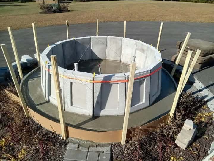 Cast concrete fountain wall panels assembled in a circle and braced with stakes while the footing cures