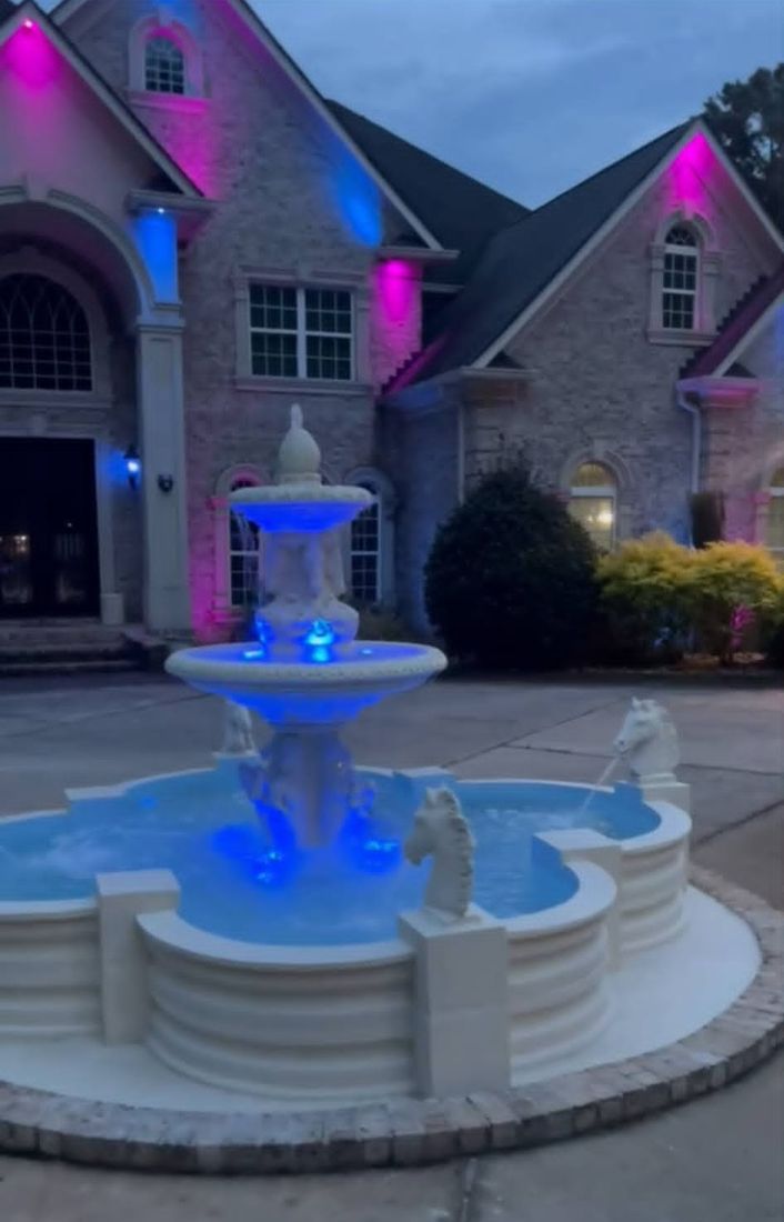 Clover fountain lit up in blue at night in front of a Georgia home