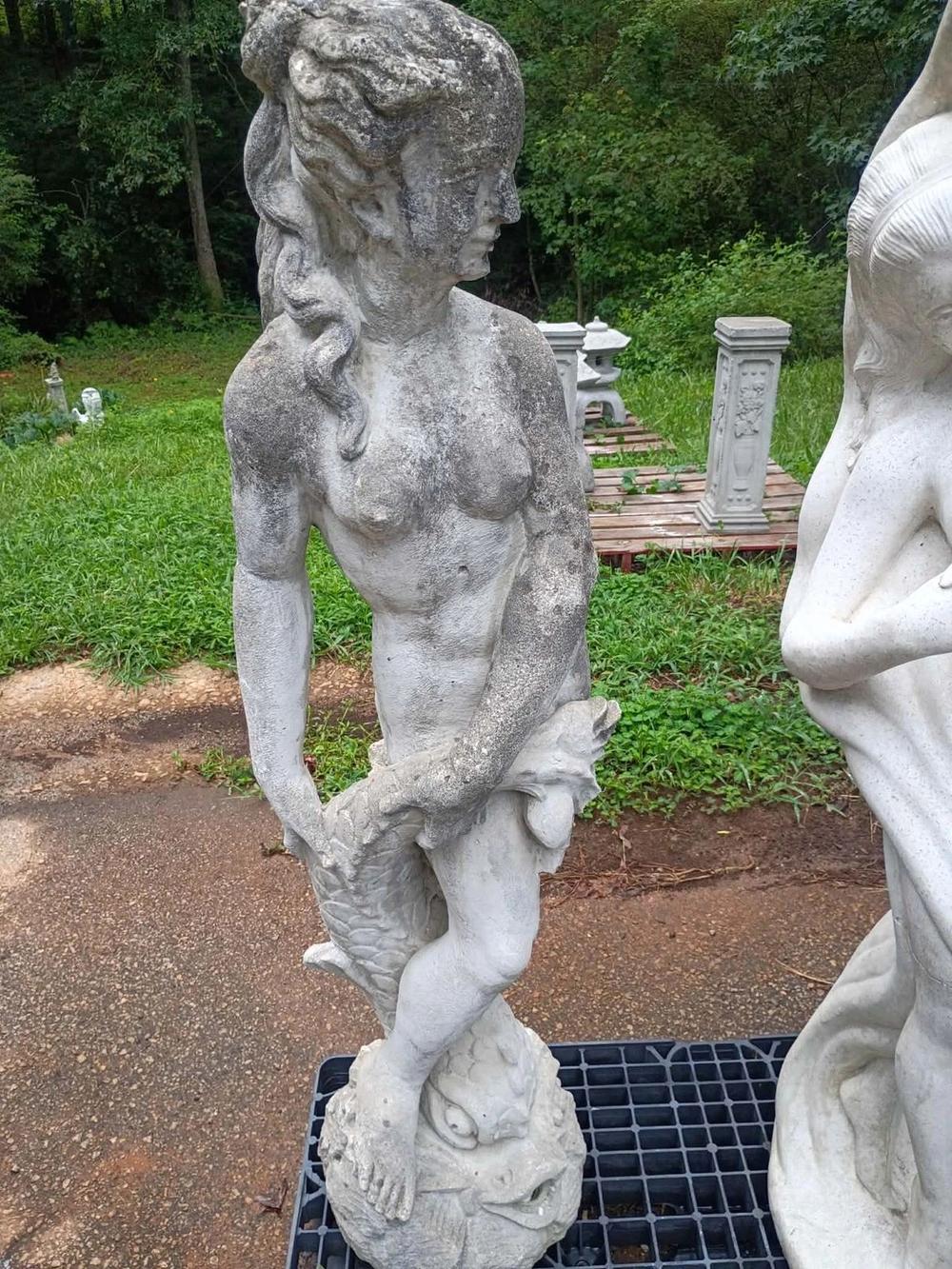 Weathered concrete statue of a classical lady with a dolphin in Villa Rica, GA