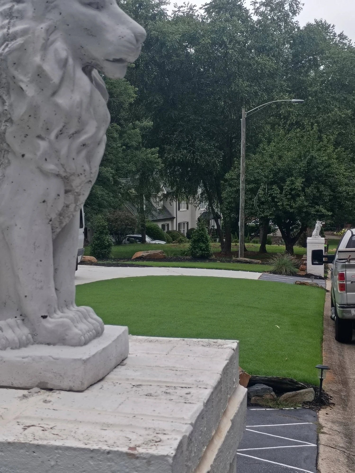 Crowned lion on a brick pillar overlooking a freshly landscaped lawn and driveway