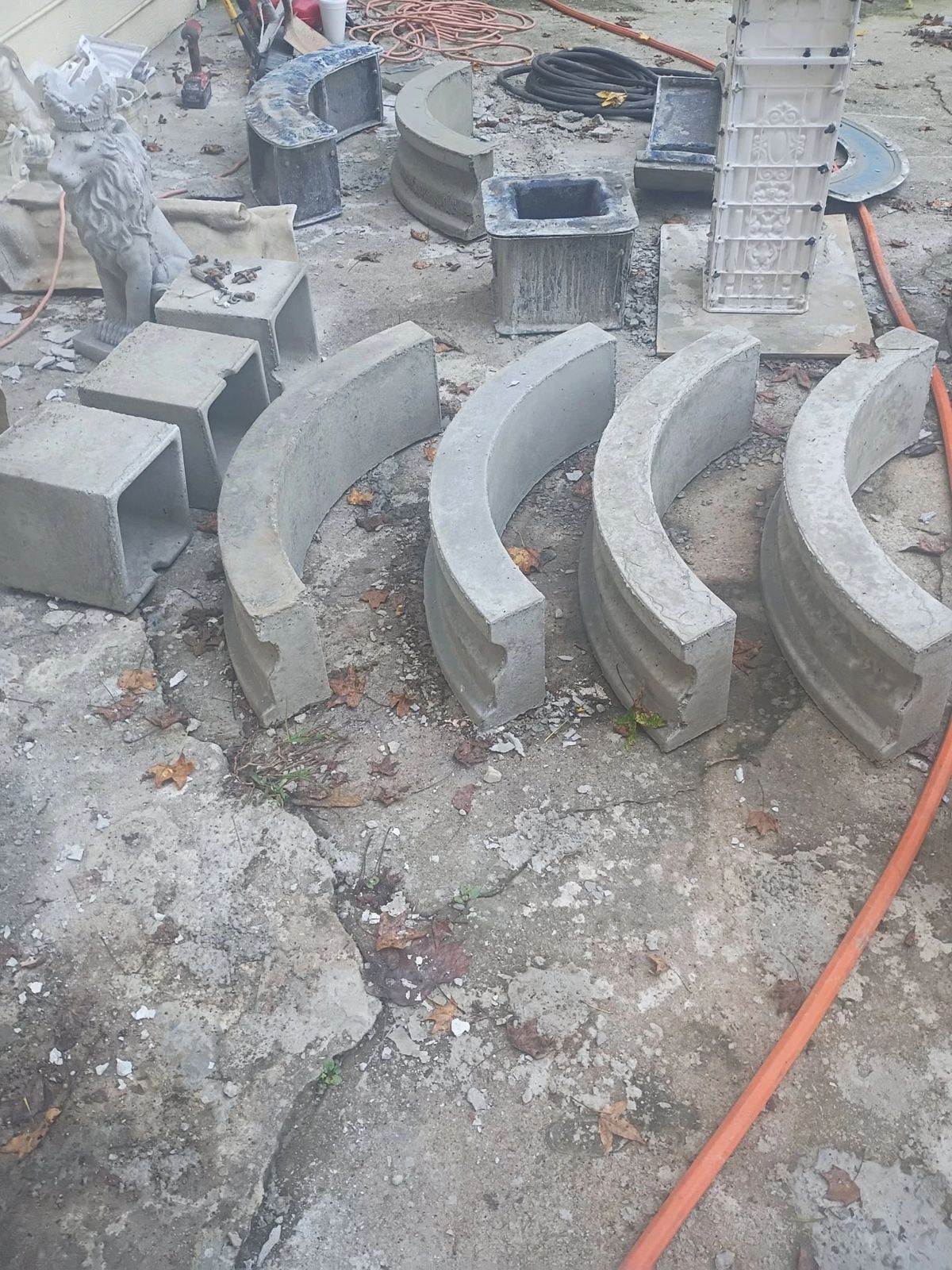 Freshly cast curved concrete pool wall sections and pedestal blocks for The Majestic laid out on the shop pad