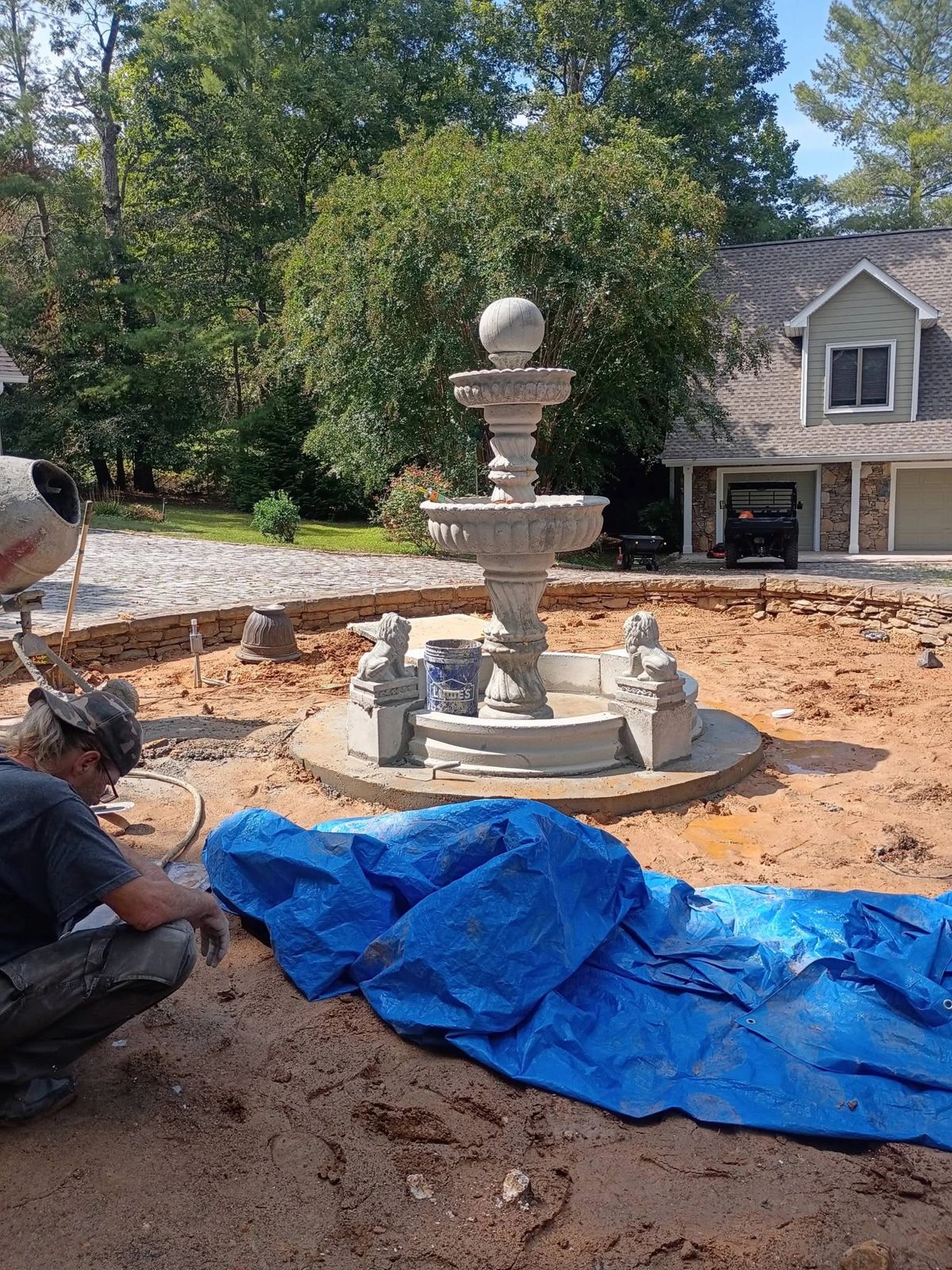 Chris setting the lions on the newest Majestic fountain in a stone-walled driveway circle