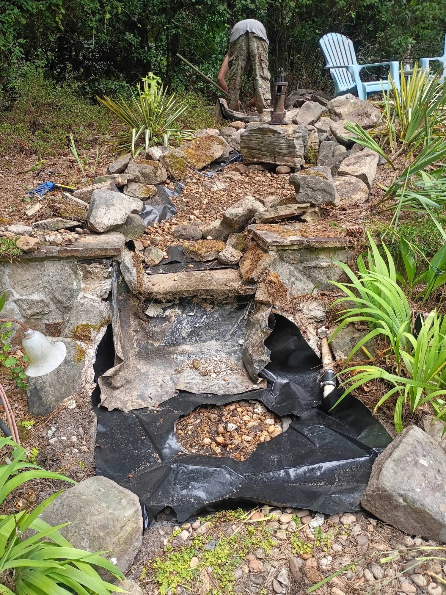 Backyard pond waterfall before repair with a failing torn liner