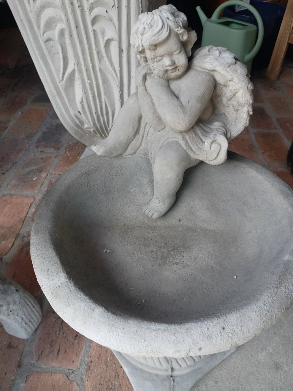 Concrete bird bath with a sitting cherub on the rim on display at Red Door Antiques in LaGrange, GA