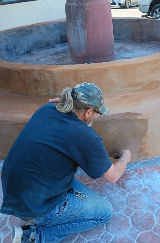 The owner hand-finishing the stain on the restored fountain wall