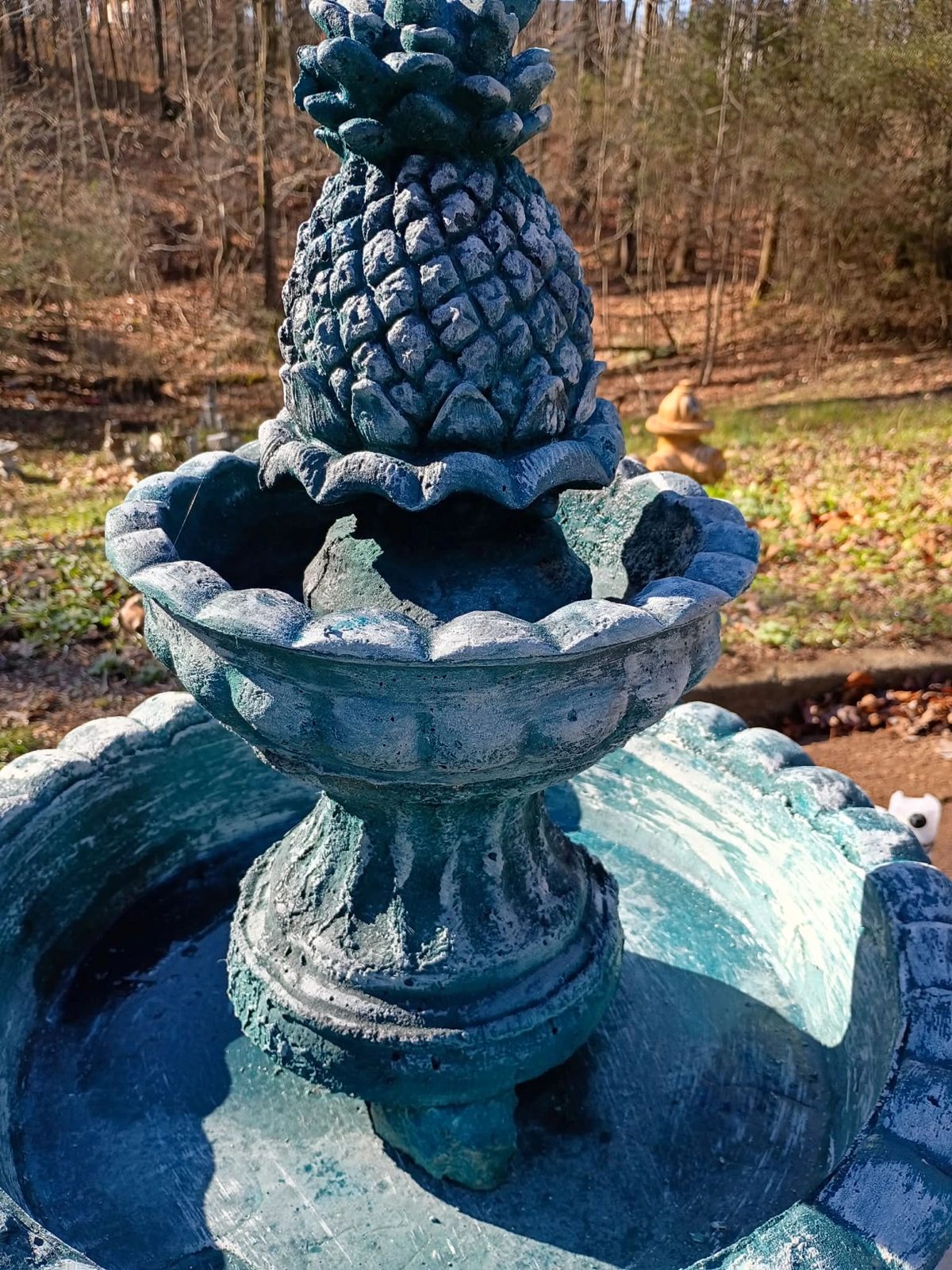 Close view of the pineapple top on a teal two-tier fountain at its new home